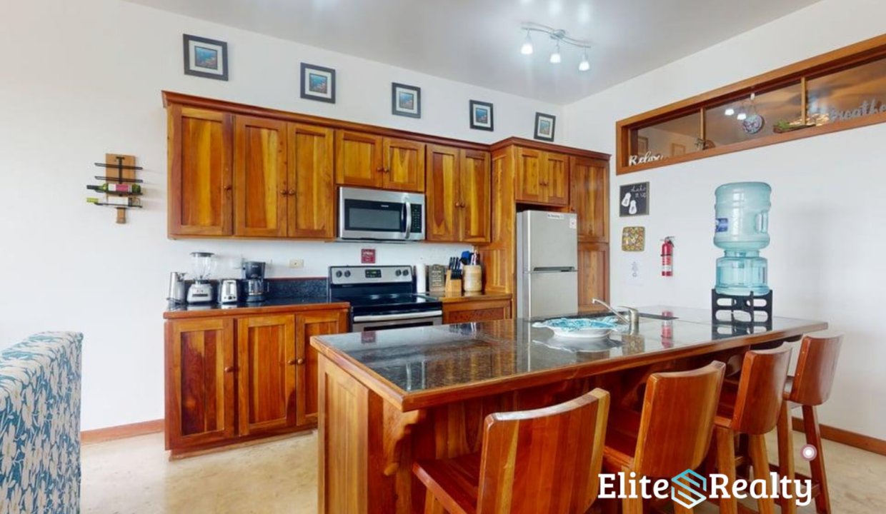 Wood Kitchen With Island Seating Granite Countertop And Appliances In Waterfront Condo At Brahma Blue Belize