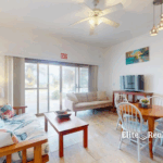Bright living and dining area with sliding glass doors at beachfront condo Blue Water Beach Resort Belize