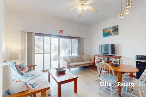 Bright living and dining area with sliding glass doors at beachfront condo Blue Water Beach Resort Belize