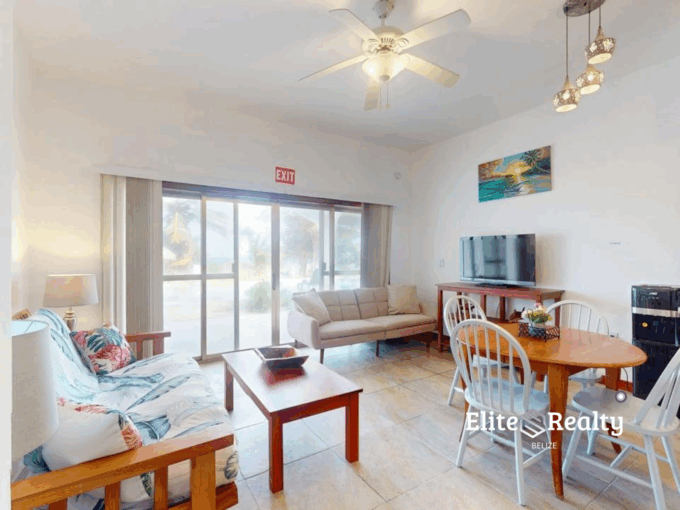 Bright living and dining area with sliding glass doors at beachfront condo Blue Water Beach Resort Belize